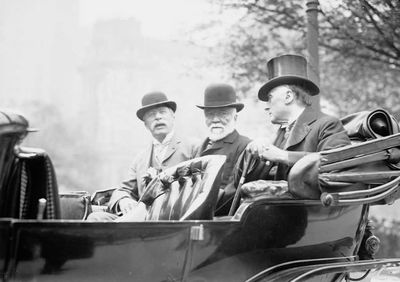 Das Schwarz-Weiß-Foto von 1913 zeigt drei Männer, einer mit einem Vollbart, einer mit einem Schnauzer, alle drei in Anzügen, mit Melonen auf dem Kopf, einer mit einem Zylinder. Alle drei sind schon äter, sie sehen aus wie ich mir Bänker oder Politiker aus der Zeit vorstelle.