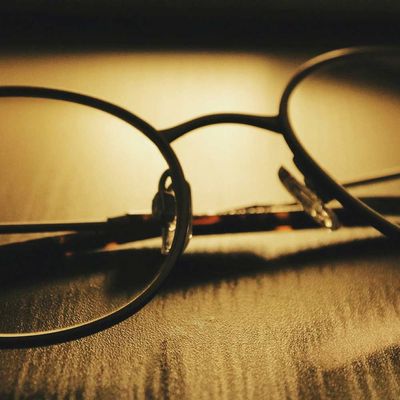 Eine zusamengefaltete, dünnrandige Brille in Nahaufnahme auf einem Tisch liegend, der Hintergrund ist nicht zu erkennen.