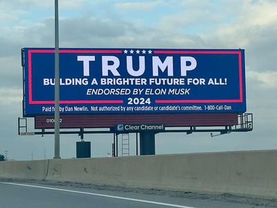 Eein Werbeplakat, das an einer Autobahn in den USA aufgestellt ist. Es handelt sich um ein großes digitales Billboard mit folgender Aufschrift: TRUMP – BUILDING A BRIGHTER FUTURE FOR ALL! – ENDORSED BY ELON MUSK 2024. Unterhalb dieses Textes gibt es einen Hinweis: Paid for by Dan Newlin. Not authorized by any candidate or candidate's committee. 1-800-Call-Dan.