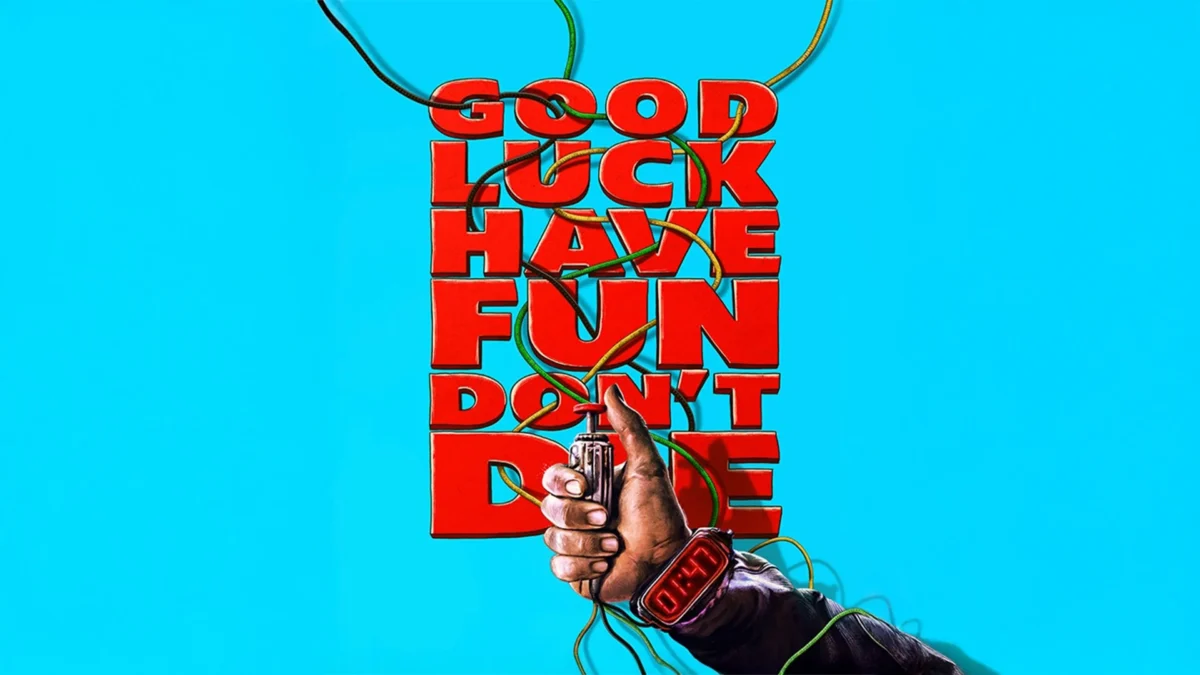Vor dem Schriftzug Good Luck Have Fun Don't Die ist der ausgetsreckte Ar eines Mannes zu sehen, der einen Zündmechanismus für eine Bombe in der Hand hät.